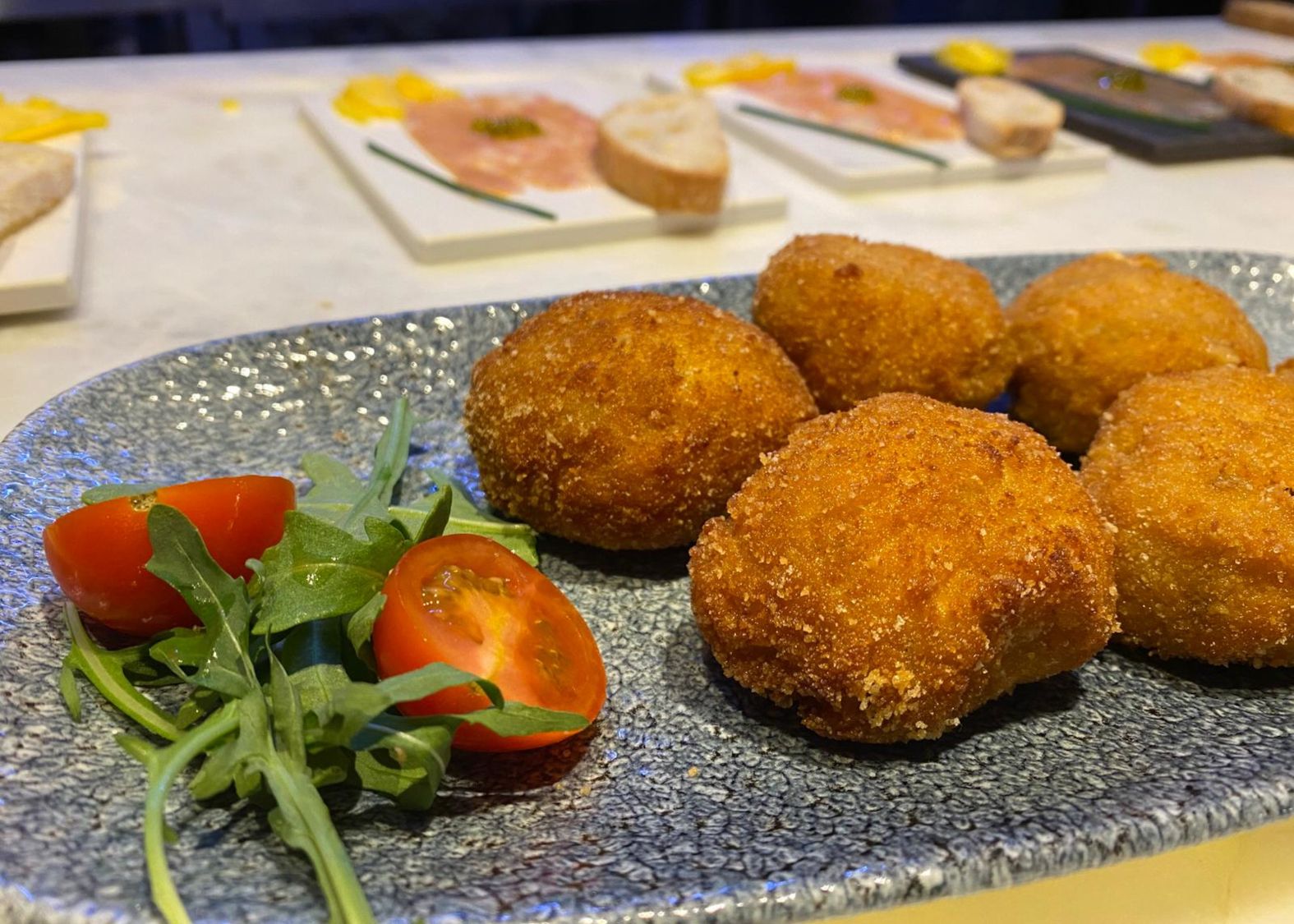 Plato con croquetas y un tomate cherry partido por la mitad